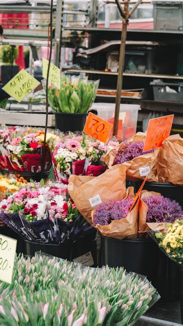 A vibrant display of fresh floral arrangements and bouquets at a flower stall, with various types of flowers including tulips, daisies, and lavender in different stages of bloom. The flowers feature a