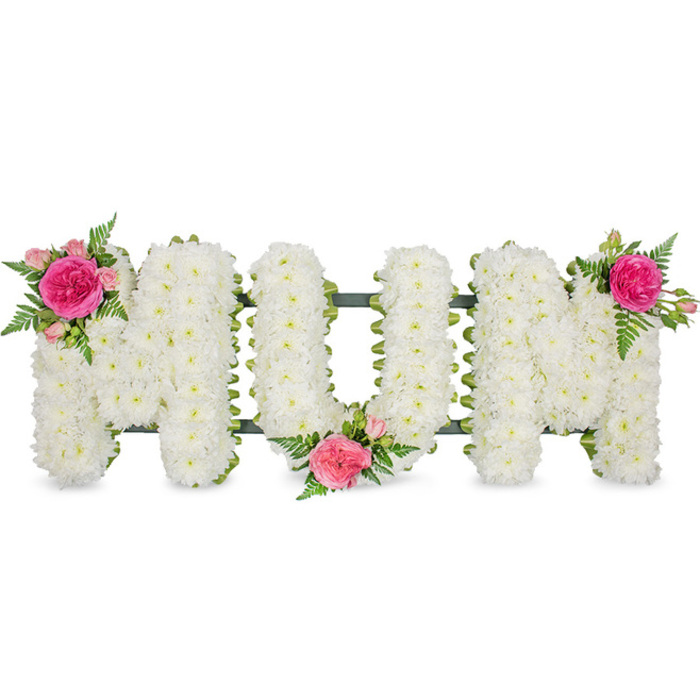 This image features a traditional funeral flower tribute spelling "MOM" in large, upright capital letters, photographed head-on against a smooth white backdrop, as if it were resting on a stand before being taken to a service in the Chase Cross area. Each letter is supported by a hidden framework, edged along the bottom with a dark green band that provides both structure and crisp definition. Over this foundation, the florist has densely arranged small white chrysanthemum blooms, their rounded petals overlapping to create a plush, even texture. The chrysanthemums are a bright, neutral white, symbolising peace and remembrance, and they cover the letters so thoroughly that the surface appears soft and gently domed. In contrast to this calm expanse, three accent flower groupings bring colour and a sense of personal sentiment. The upper left of the first "M" is adorned with a cluster of flowers featuring a fully opened fuchsia rose, its petals layered and slightly ruffled, surrounded by paler pink spray roses and tight rosebuds, all nestled among light, lacy fern foliage. This same blend of fuchsia and pink roses with airy greenery is repeated at the lower junction between the "O" and the second "M", and again at the upper right corner of the last "M", creating a balanced rhythm of colour across the tribute. The greens of the ferns and the framework introduce a natural freshness that echoes the parks and leafy streets around Chase Cross, while the pink roses speak of love, gratitude, and cherished family memories. Altogether, this "MOM" tribute feels both classic and intimate, like a carefully chosen farewell from children or grandchildren wishing to express their enduring affection at a funeral or graveside service nearby.