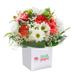Overflowing with cheerful tenderness, this skillfully arranged bouquet is staged in a flawless white square gift bag, channeling the inviting spirit of Chase Cross on a bright spring morning. The heart of the display is filled with lavish carnations in shades of warm coral, peach, and bold red, each bloom flounced with ruffled petals that seem almost to dance. Crisp white daisies, highlighted by their vibrant green-yellow eyes, weave through the arrangement, lending bursts of lightness and innocent happiness. Wisps of baby's breath drift like gentle puffs of cloud between the stars of the bouquet, their delicacy enhancing both contrast and charm. On the left, a hint of closed buds with a purple glow nestle in, promising the arrival of new beauty. All of these flourish above a bed of lush, deep green foliage with a glossy finish, creating a soothing, cradling effect akin to wandering through the greenery of Chase Cross's local parks. The practical yet elegant gift bag-complete with crisp ribbon handles-elevates the bouquet for gifting or doorstep delivery. Each stem has been thoughtfully placed, forming a full and rounded shape that feels abundant and sincere. The whole tableau glows under soft light, accentuating freshness and care-a perfect choice to mark a birthday, celebrate new beginnings, or simply put a smile on someone's face. This arrangement is crafted as only a true local florist could, with knowledge, artistry, and a heartfelt connection to the community.